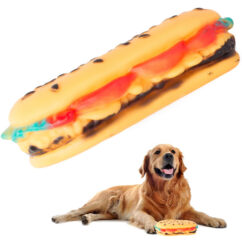Koera mänguasi kummist valmistataud kollane hot dog sai, mille kõrval istub suur koer.